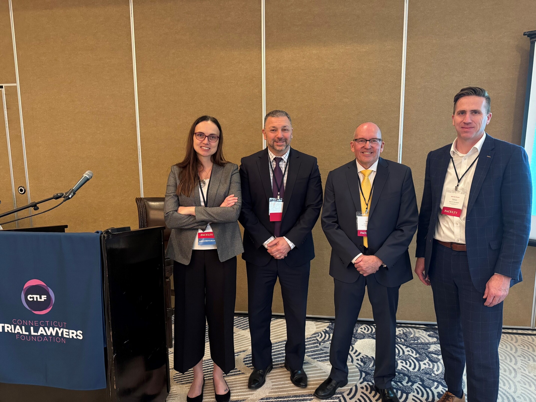 Four attorneys stand behind the podium after teaching a seminar.