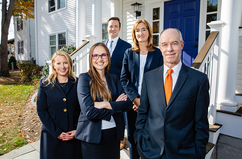 Five attorneys in suits standing outside the Walsh Woodard office.