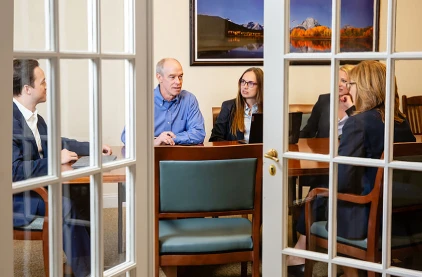 Five attorneys seated around a conference table, viewed from outside the conference room.